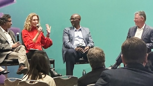 Amy Klement of Imaginable Futures sitting on a panel with three other speakers. Behind them is a backdrop that says "ASU + GSV Summit"