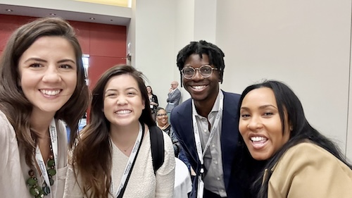 Enyi Okebugwu of Imaginable Futures and three other people stand in a conference room and are smiling.