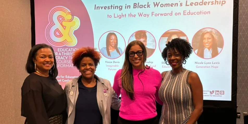 Four women smile in front of a presentation screen with the title "Investing in Black Women's Leadership to Light the Way Forward on Education."