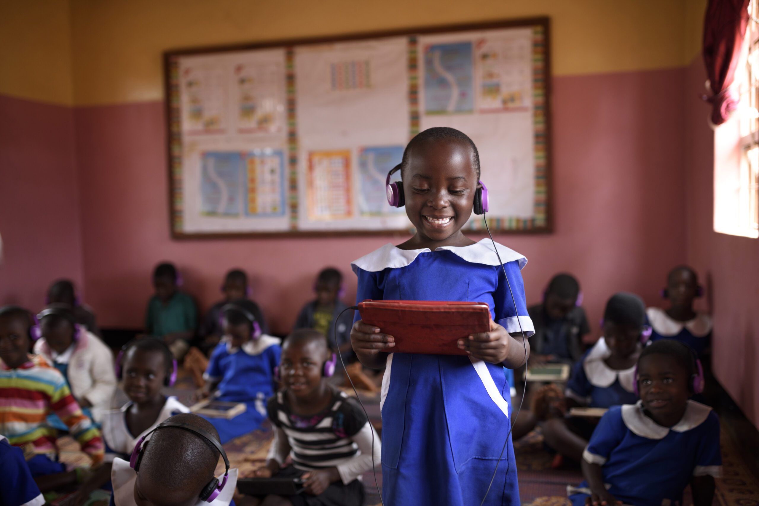 child with headphones and a tablet smiling