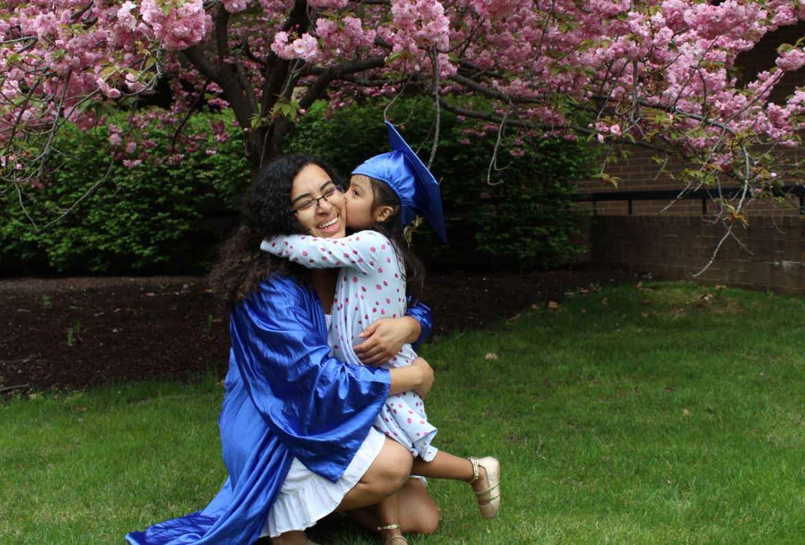 Graduating mom in cap and gown with her daughter.