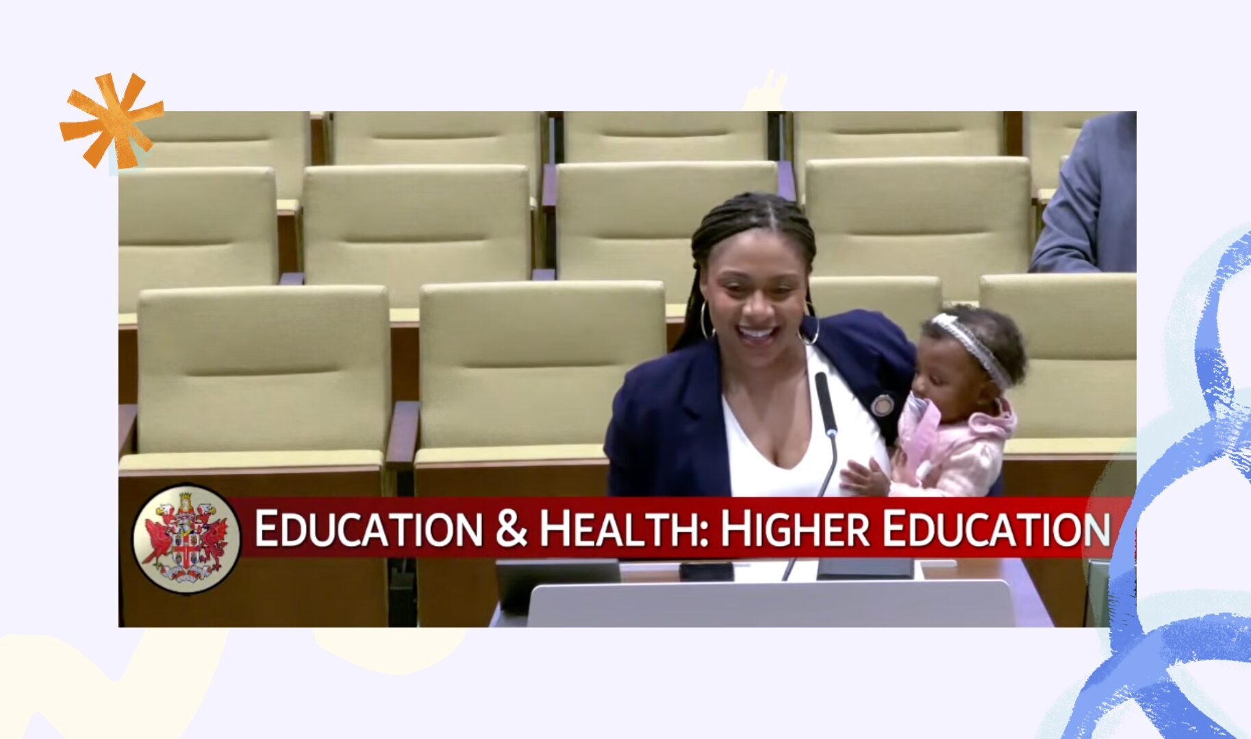 Woman elected official presents before a committee while holding her infant daughter.